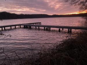 a dock on a body of water at sunset at Lake idyll Comfortable holiday residence in Repente +3 photos