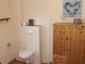 a bathroom with a toilet and a wooden cabinet at Boddensurfer 2b Comfortable holiday residence in Pruchten