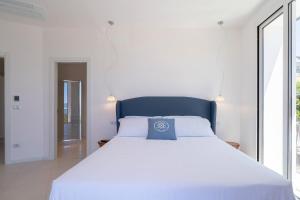a bedroom with a white bed with a blue pillow on it at Dimore delle Zagare Molo in Syracuse