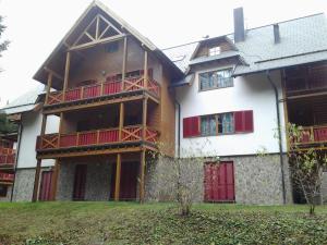 un gran edificio de madera con balcones rojos. en Holiday Apartment Bolfenk, en Hočko Pohorje
