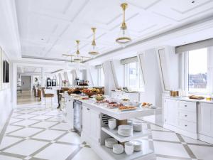 a white kitchen with a large island with food on it at The Langham London in London