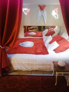 a bedroom with two beds with red and white sheets at Love Room Ange ou Démon à Aulnat in Aulnat