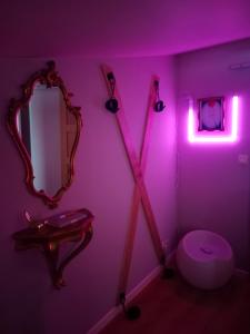 a bathroom with a pink lighting and a mirror and a toilet at Love Room Ange ou Démon à Aulnat in Aulnat