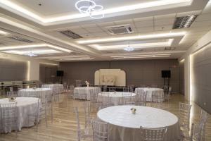 un salón de banquetes con mesas y sillas blancas en ALVEA HOTEL, en Puerto Princesa City