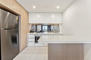 een keuken met witte kasten en een koelkast bij Mega Style Apartments Kings Domain in Melbourne