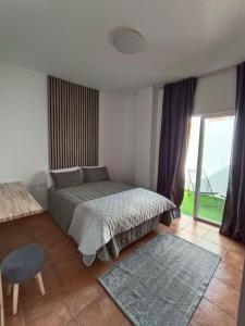 Un dormitorio con una cama y una ventana grande. en La atalaya, en Sauzal