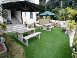 un patio con 2 mesas de picnic y una sombrilla en La Residence D'Almee Guesthouse en Anse Possession