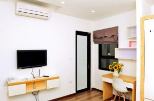 Zimmer mit einem Schreibtisch und einem TV an der Wand in der Unterkunft Era Apartment Nguyen Van Huyen in Hanoi