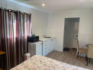1 dormitorio con 1 cama, lavamanos y mesa en Blue Sapphire Village Pet Friendly, en Glen Innes