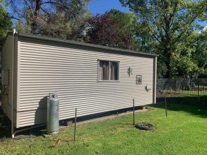 a small white shed with a window in a yard at Blue Sapphire Village Pet Friendly in Glen Innes