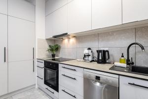 a kitchen with white cabinets and a stainless steel appliance at Cayenne Premium Apartment Airport in Warsaw