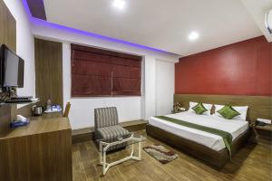 a bedroom with a bed and a tv and a chair at Treebo Trend Edge St Marks Road in Bangalore
