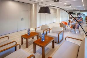 una sala de espera con sillas y mesas blancas en GHT Oasis Tossa & Spa, en Tossa de Mar