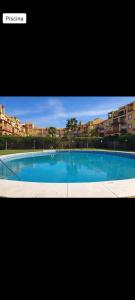 een groot blauw zwembad met gebouwen op de achtergrond bij Paola´s Costa Esuri, Albatros-Golf in Ayamonte