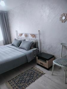1 dormitorio con 1 cama, 1 silla y 1 mesa en Уютная 2 ком-я квартира в центре города, район "Арбата" en Almaty