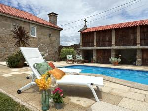 a white chair sitting next to a swimming pool at Conde Dúplex - Casal do Conde in Caldas de Reis