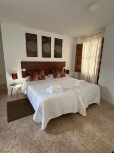 1 dormitorio con 1 cama blanca grande y toallas. en Alojamiento La Escalera, en Alhama de Granada