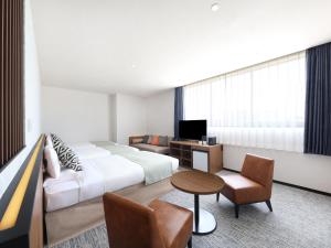 a hotel room with a bed and a couch and a table at HOTEL MYSTAYS Kumamoto Riverside in Kumamoto