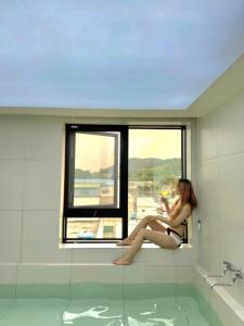 a woman sitting in a window in a bath tub at Hound Hotel Gijang Osiria in Busan