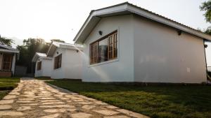 a white house with a stone driveway at Saanjh Cottages - Hotel in Bir Billing in Bīr