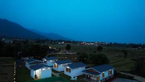 a row of houses in a field at night at Saanjh Cottages - Hotel in Bir Billing in Bīr