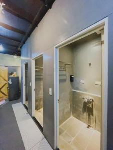uma casa de banho com um chuveiro e uma porta de vidro em The Hostel By The Sea em Green Island