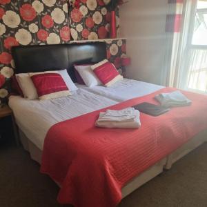 a bed with a red blanket and two towels on it at The Fawley Guest house in Shanklin