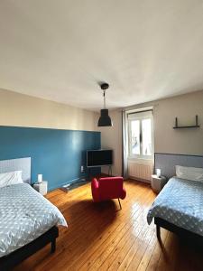 a bedroom with two beds and a red chair at Appartements Plantagenet - Le 33 in Le Mans
