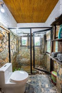 uma casa de banho com um WC e uma parede de pedra em Lim's house em Mai Châu