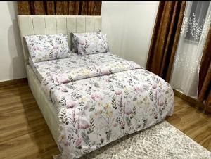 Tammy Homes stay في دار السلام: سرير مع لحاف الزهور والوسائد