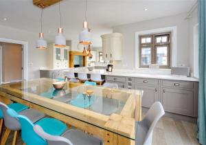 a kitchen with a glass table and blue chairs at Hafan Dawel in Abersoch