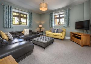 a living room with a leather couch and a television at Hafan Dawel in Abersoch