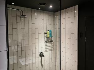 um chuveiro na casa de banho com paredes em azulejos brancos em Modern apartment with balcony em Cidade do Cabo