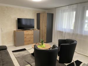 uma sala de estar com uma mesa e cadeiras e uma televisão em Ferienwohnung Palmengarten em Lichtenstein