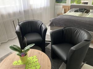 twee zwarte stoelen en een tafel in een slaapkamer bij Ferienwohnung Palmengarten in Lichtenstein