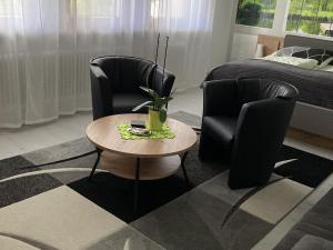uma sala de estar com duas cadeiras, uma mesa e uma cama em Ferienwohnung Palmengarten em Lichtenstein