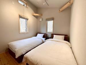 two beds in a room with two windows at THE LIVIDA 軽井沢west コナラテラス in Karuizawa