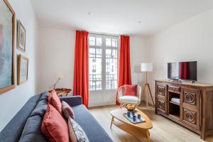 sala de estar con sofá azul y cortinas rojas en Résidence Hostin'Malo - Au cœur de Saint Malo, en Saint-Malo