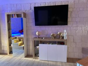 un salon avec une télévision sur un mur en briques dans l'établissement B&B Villa Cassandra, à Castellana Grotte
