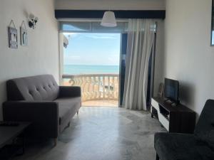 a living room with a couch and a large window at Maison Seaview Suites Port Dickson in Port Dickson
