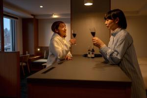 美瑛町にある湯元　白金温泉　ホテルの二人の女性がワインを飲みながらカウンターに立っている
