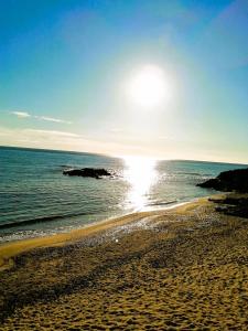 a beach with the sun shining on the water at Rêve D'azur, Plage à Pied, Piscine, Parking & Terrasse BBQ, Wifi et Draps Inclus en Bord de Mer à La Nartelle in Sainte-Maxime