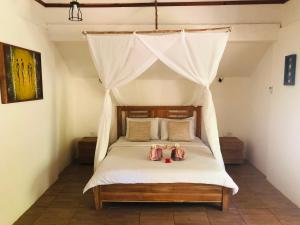 Meno Dream Resort في غيلي مينو: غرفة نوم بها سرير مظلة مع وجود دميتين عليها