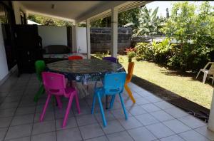 - une table avec des chaises colorées sur la terrasse dans l'établissement A TOMO MAI, à Uturoa