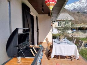 a patio with a table and a television on a porch at Maison de montagne in Saint Firmin