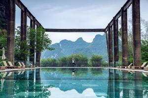 a swimming pool with mountains in the background at Yangshuo Sugar House in Yangshuo