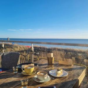 - une table en bois avec deux tasses de café et une vue sur l'océan dans l'établissement Apartament Perła Juraty, à Jurata