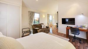 a room with a bed and a couch and a television at Grace Cottages in Uralla