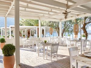 um pátio com mesas e cadeiras brancas e o oceano em Grecotel Filoxenia Hotel em Kalamata