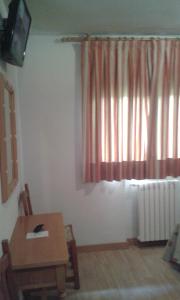 a room with a table and a window with a radiator at Hotel Rural Marcos in Rascafría